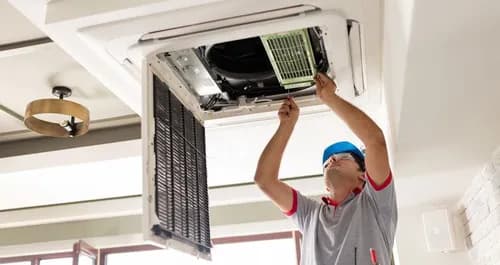 Tecnico instalando aire acondicionado tipo cassette de techo en local comercial